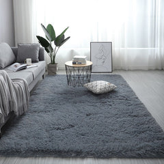 Soft dark grey nordic fluffy bedroom rug on a light wooden floor in a bright modern living room setting.