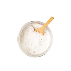 ayurvedic coconut milk bath soak in a glass jar with a wooden spoon
