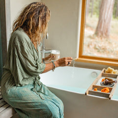 Woman preparing to use ayurvedic coconut milk bath soak in a serene bathroom setting.