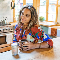 A woman enjoying a warm cup from the ayurvedic herbal tea collection in a cozy kitchen.