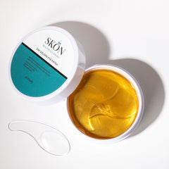 24k golden eye patches in an open container with a clear applicator spoon, showcasing the luxurious hydrogel texture.
