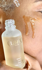 vegan glow up toner serum bottle with serum on skin close-up