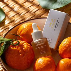 ayurvedic amla oil for face and hair bottle beside fresh oranges