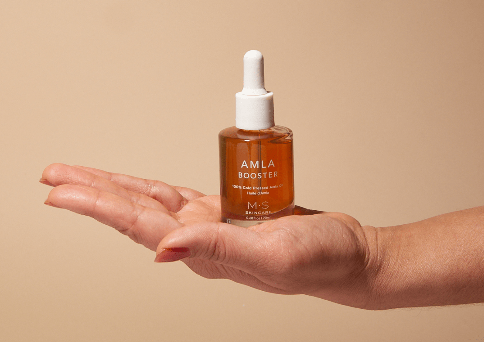 ayurvedic amla oil for face and hair bottle held in hand
