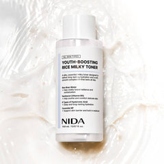 NIDA Youth-Boosting Rice Milky Toner 150ml bottle on a creamy background, promoting hydration and brightness.