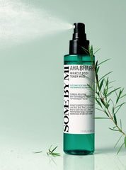 SOME BY MI AHA BHA PHA body mist green bottle spraying fine mist next to green leaves.