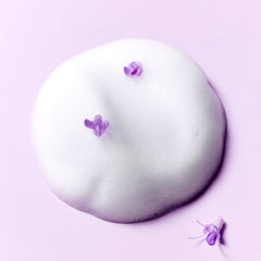 White foam texture of SOME BY MI retinol bakuchiol bubble toner with purple flowers on a lilac background.