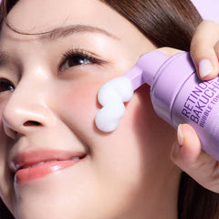 Woman applying fluffy SOME BY MI retinol bakuchiol bubble toner foam onto her glowing cheek.