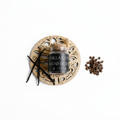 Vanilla Latte Sugar Scrub in a jar on a decorative tray with coffee beans and vanilla pods.