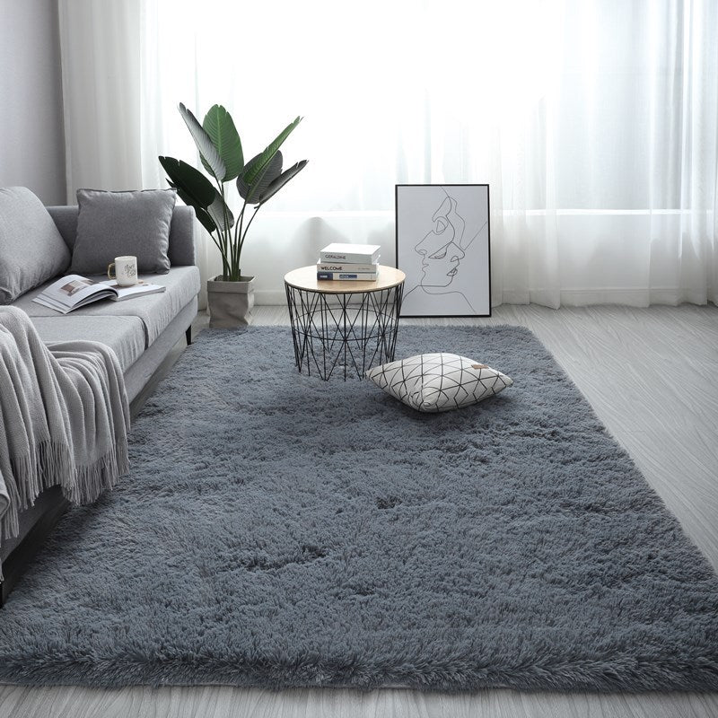 Soft dark grey nordic fluffy bedroom rug on a light wooden floor in a bright modern living room setting.