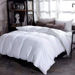 Fluffy white winter goose down duvet draped on a bed with pillows in a modern bedroom.