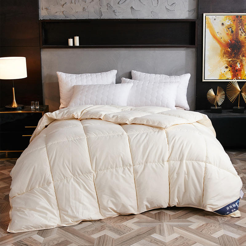 A fluffy Creamywhite winter goose down duvet on a modern bed with white pillows.