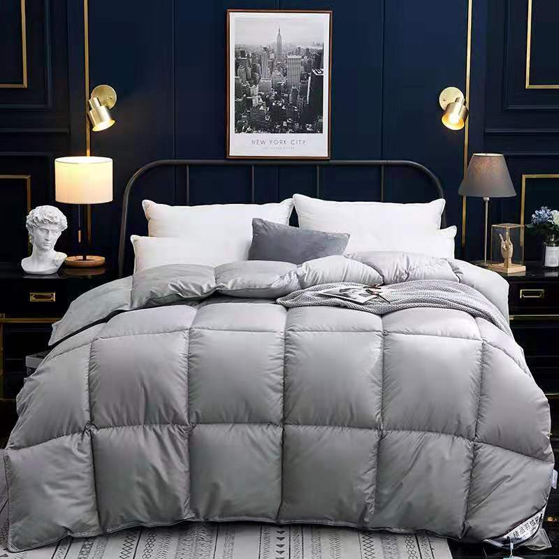 Grey winter goose down duvet on a bed in a modern, elegantly styled bedroom.