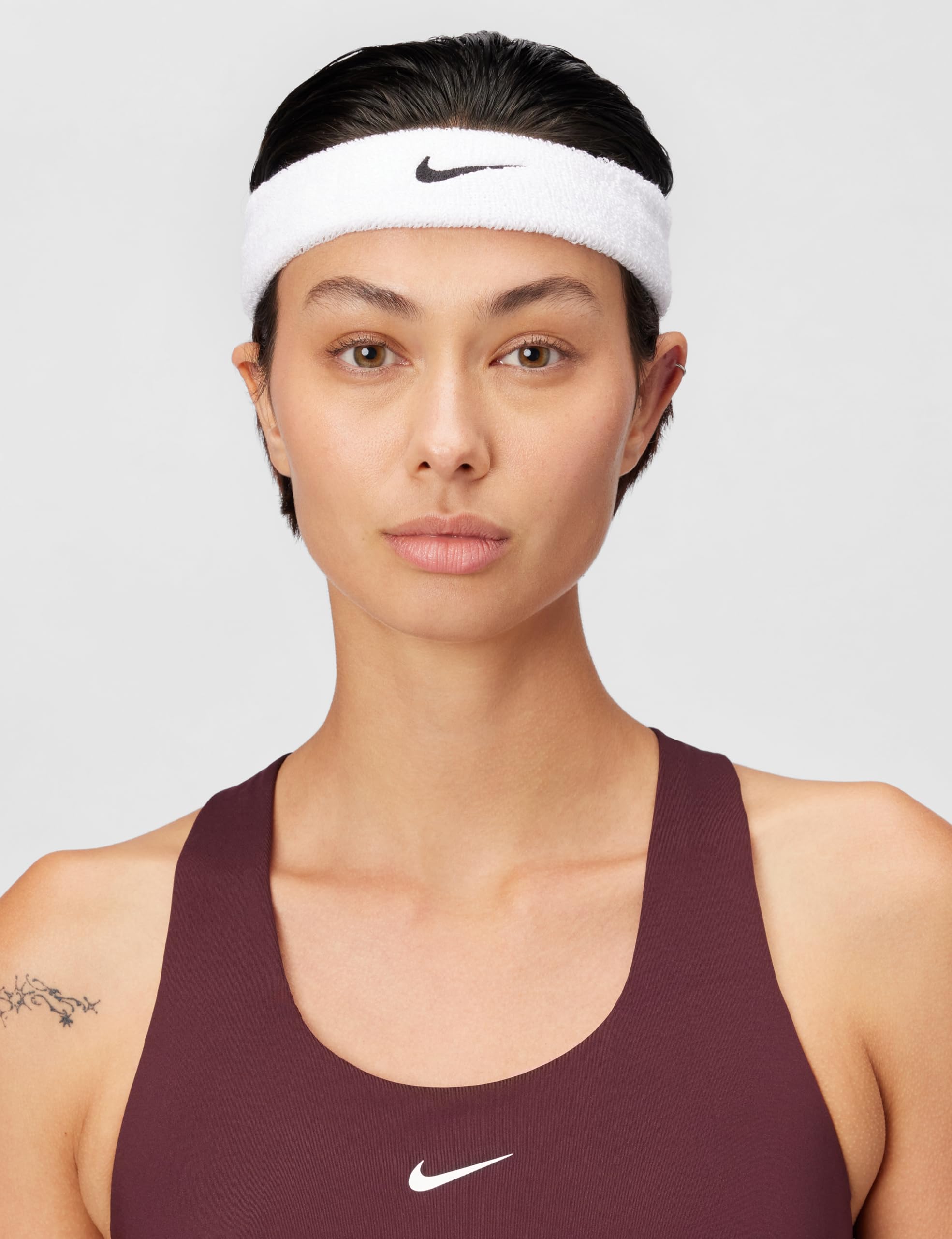 Nike Swoosh classic headband worn by a model with a sleek hairstyle and athletic top.