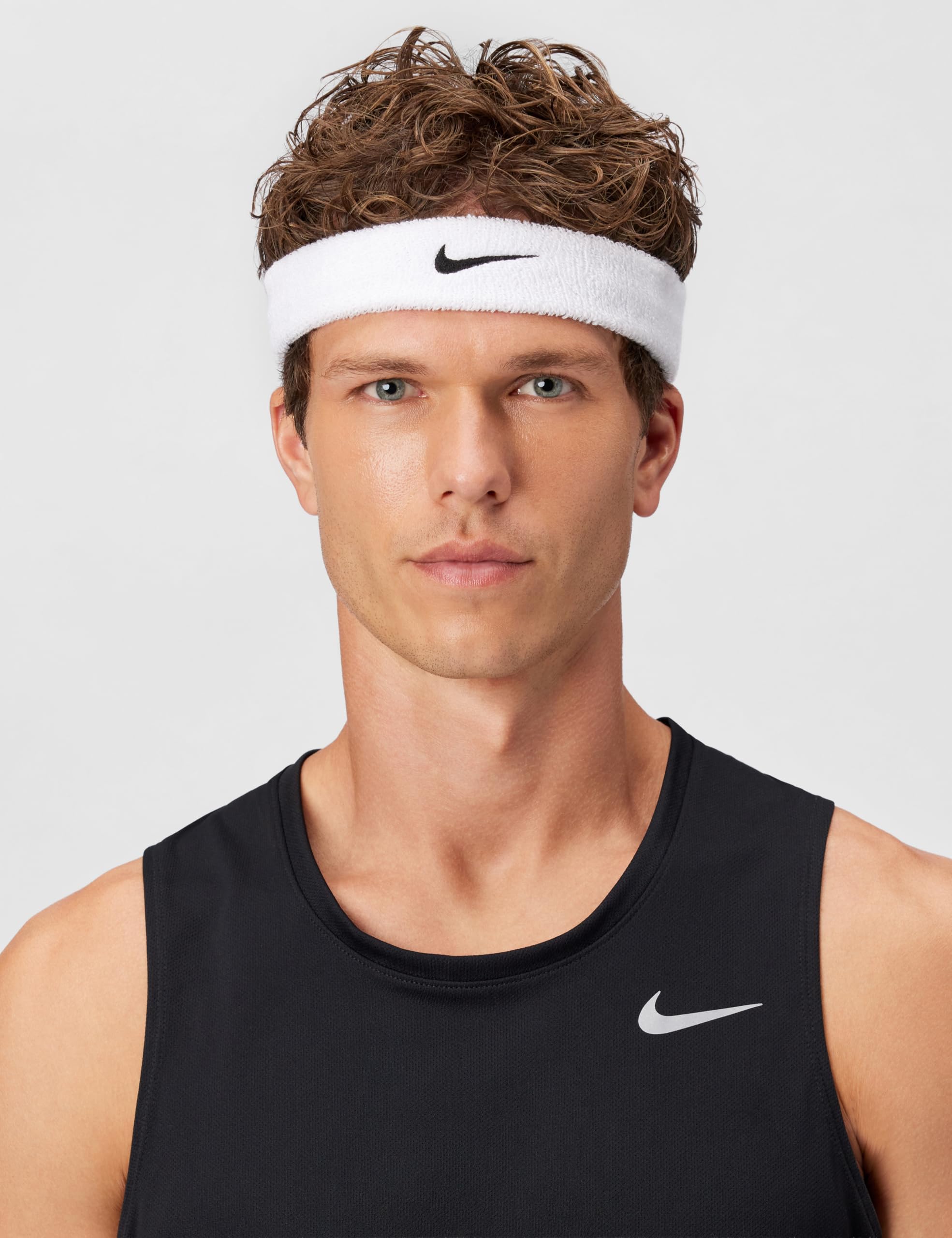 Nike Swoosh classic headband worn by a male model with short, curly hair and a black tank top.