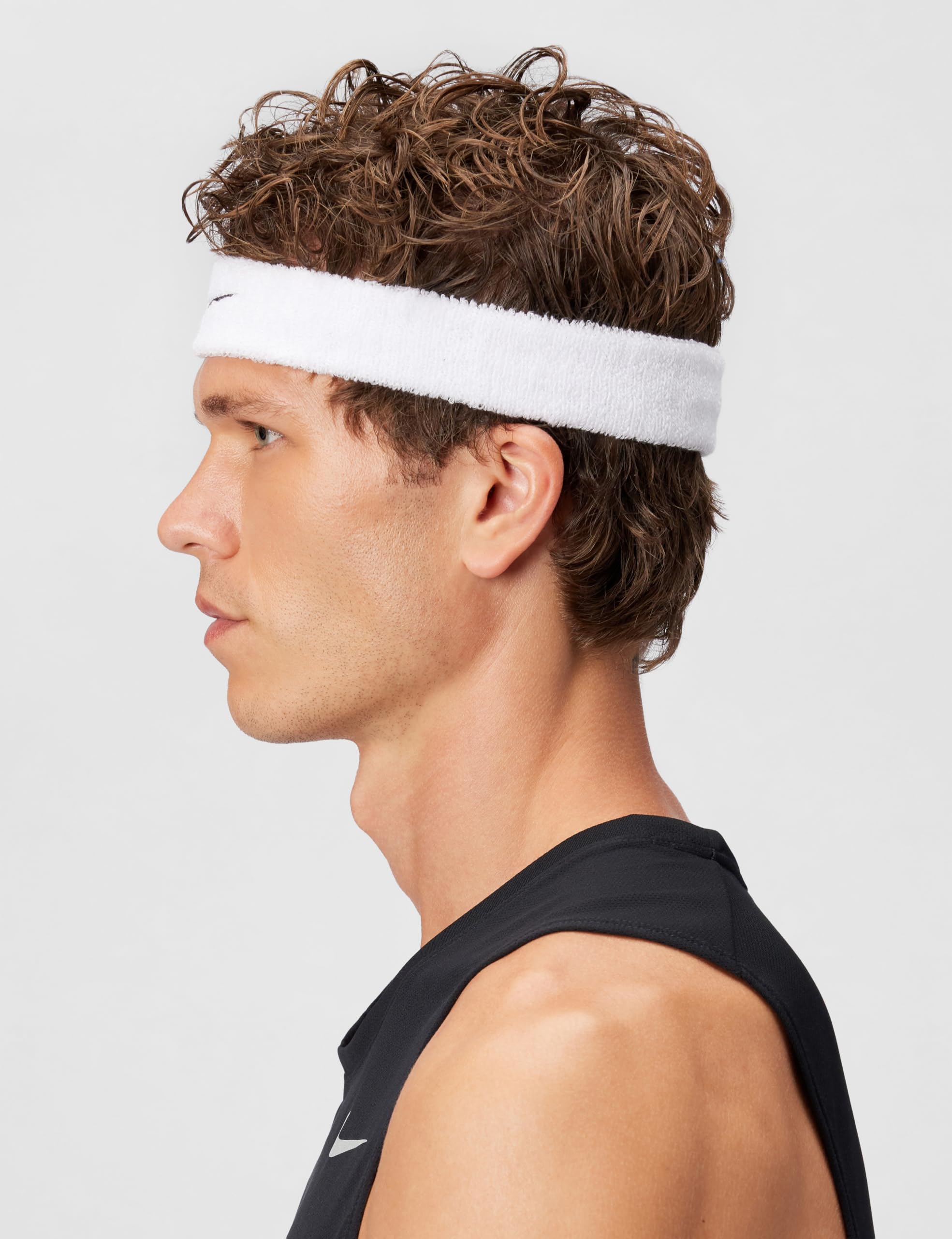 Nike Swoosh classic headband worn by a man with curly hair in profile view.