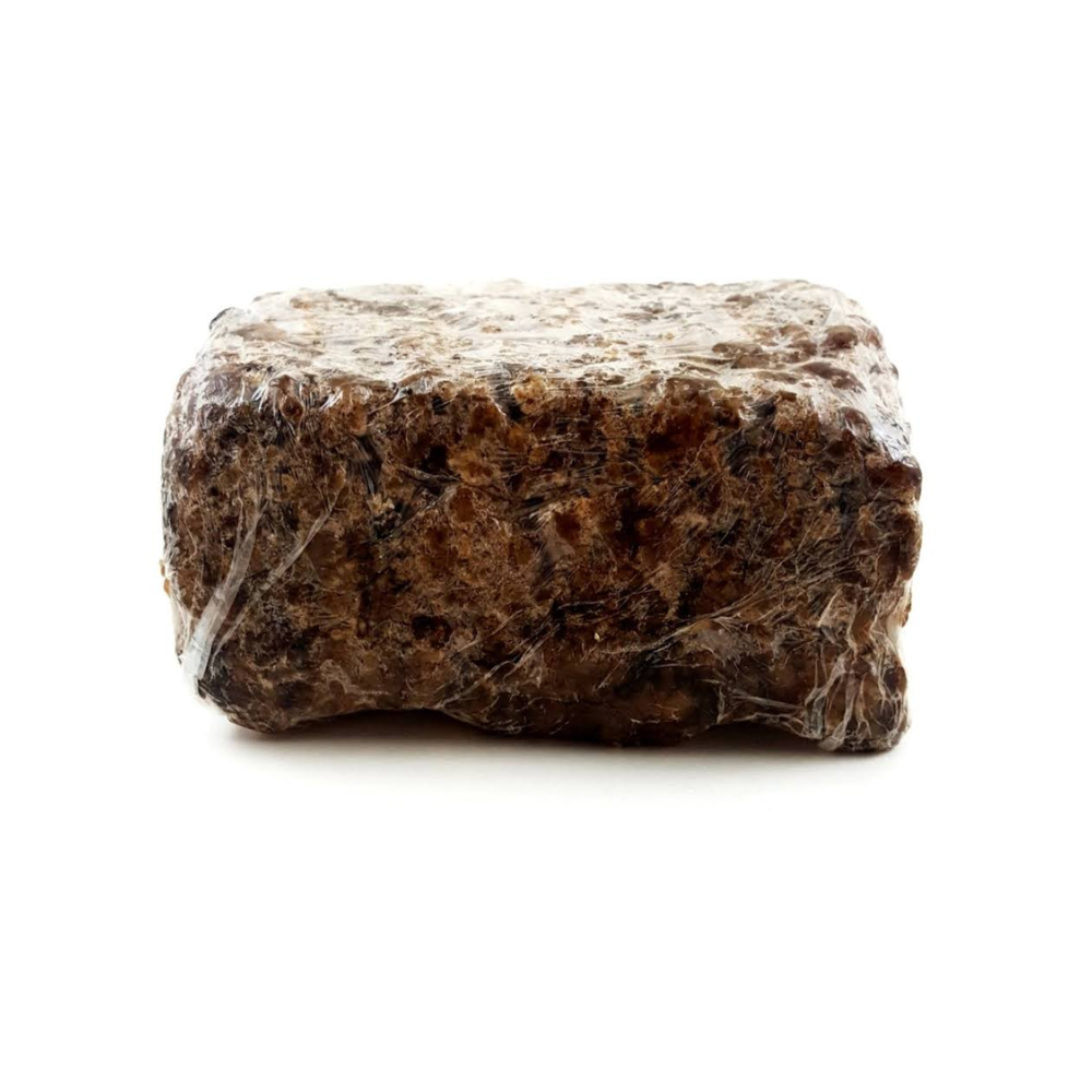 Handcrafted block of raw african black soap wrapped in clear plastic film for healthier skin.