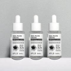 snail mucin ginseng serum three ampoules lined up on a gray background