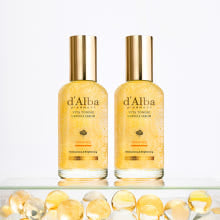 d'Alba Vita serum with vitamin capsules displayed on clear glass with golden cap bottles and capsules in foreground