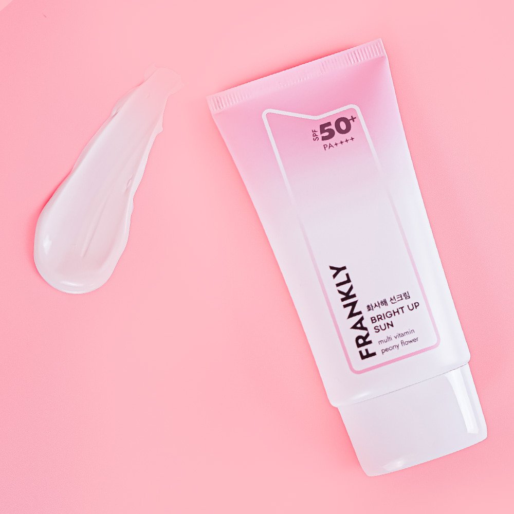FRANKLY Bright Up Sun SPF50+ PA++++ tone-up mineral sunscreen SPF50+ with a creamy texture on a pink background.
