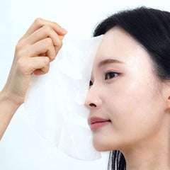 Model applying FRANKLY Closer Pore Minimizing Sheet Mask to her face for skincare routine.