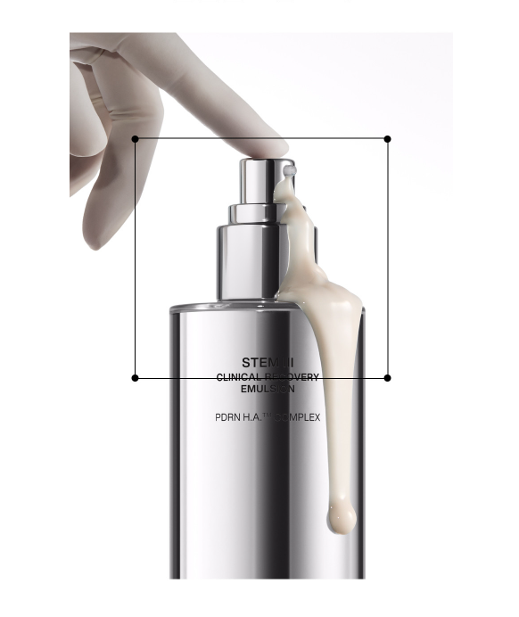 Creamy IOPE STEM III Emulsion flowing down the side of a sleek silver pump bottle pressed by a gloved finger.