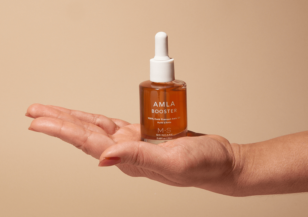 ayurvedic amla oil for face and hair bottle held in hand