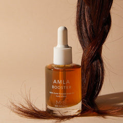 ayurvedic amla oil for face and hair in a glass bottle with dropper next to a braid of hair