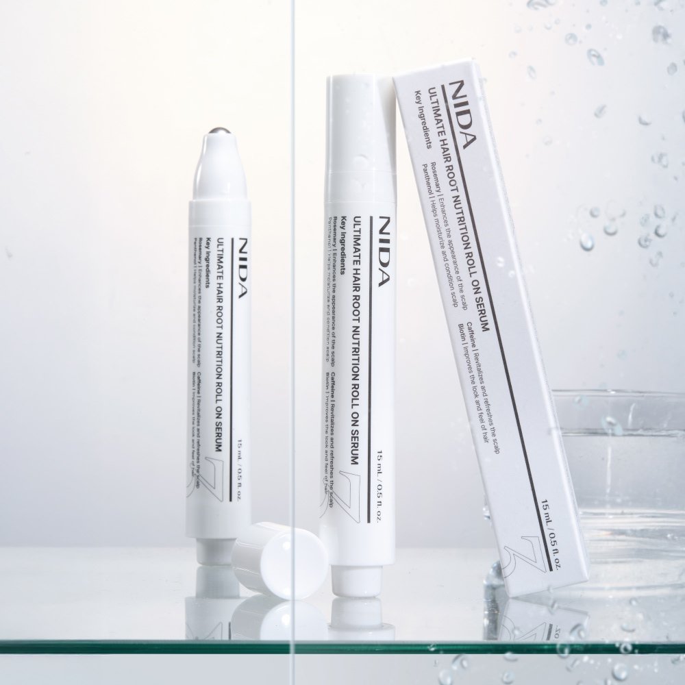 NIDA Ultimate Hair Root Nutrition Roll On Serum 15ml bottles on display with water droplets.