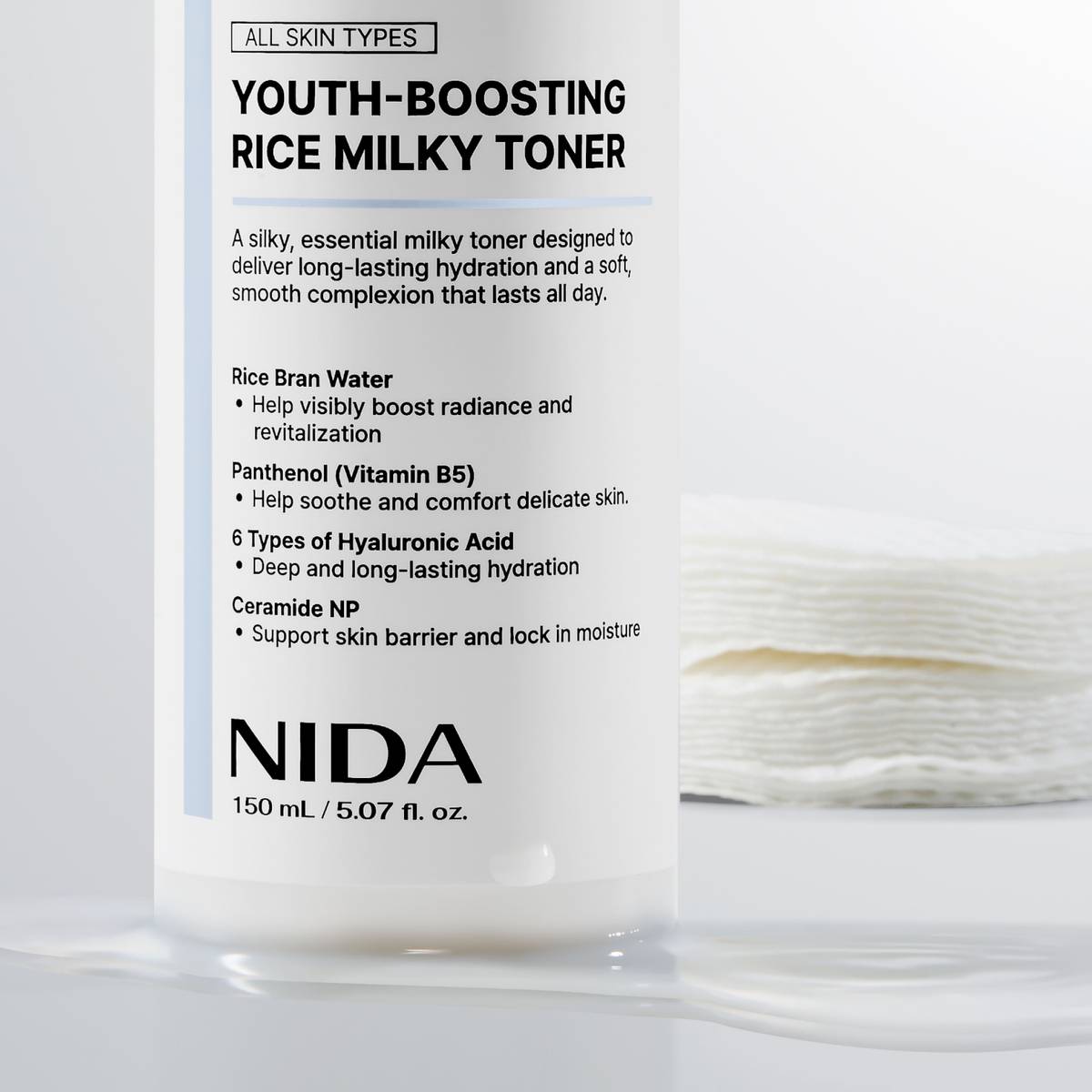 NIDA Youth-Boosting Rice Milky Toner 150ml bottle with cotton pads in the background, showcasing hydrating properties.