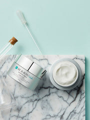 nourishing moisturizer for dry skin REJURAN Healer Nutritive Cream displayed on a marble surface with pipette and jar.
