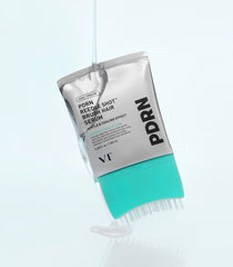 Clear liquid pouring over a silver tube of VT PDRN Reedle Shot hair serum with a teal built-in massage brush for scalp care.